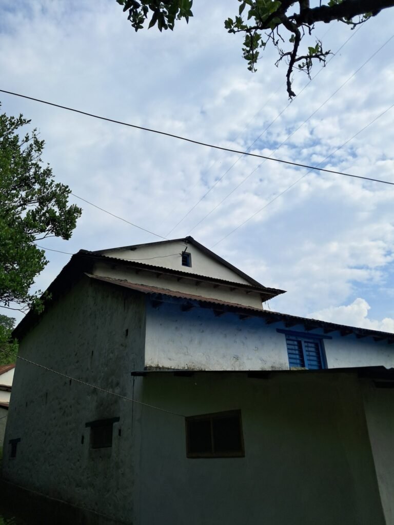 A two-story house partially visible in the image, featuring a textured white exterior and a blue accent on the upper level.