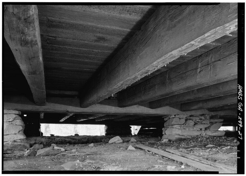 Wood floor beams and joists seen from a crawl space
