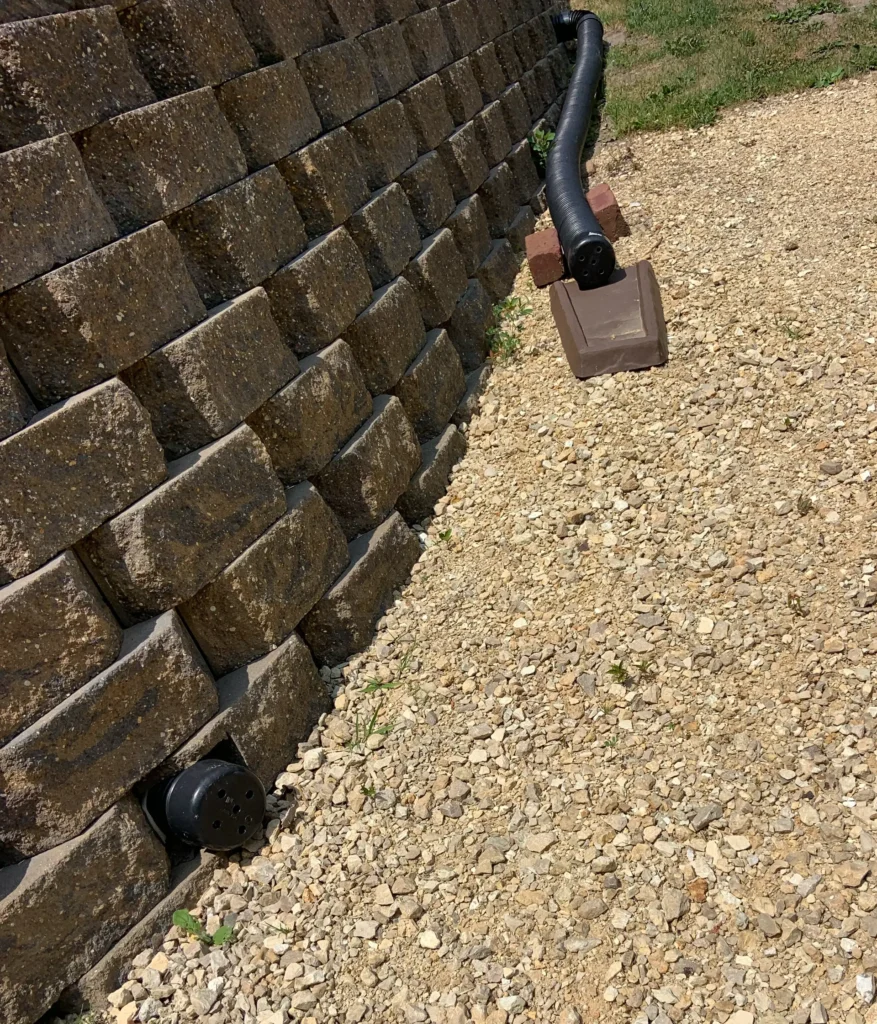 A French drain carrying gutter water away from a retaining wall